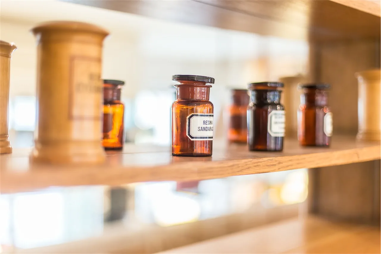 Historische Standgefäße aus Holz und braune Apothekerflaschen auf einem Holzregal